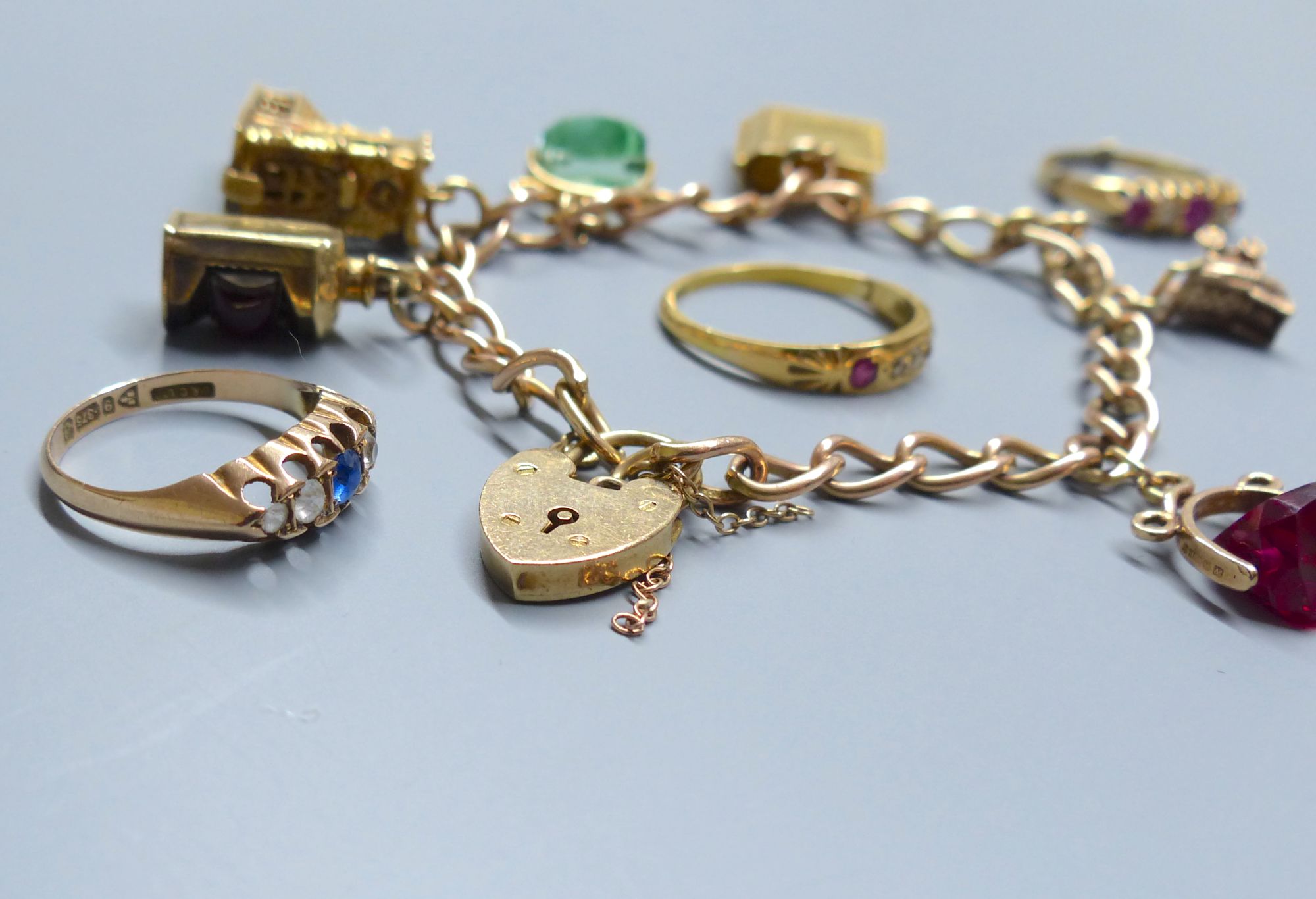 A 9ct gold charm bracelet, hung with six assorted charms including 9ct gold and 3 rings.